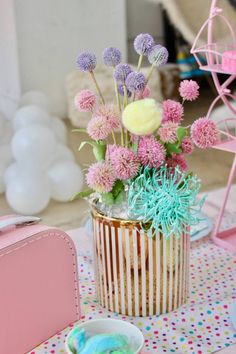 a pink suitcase sitting on top of a table next to a vase filled with flowers