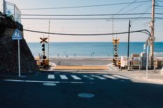 an empty street next to the ocean with traffic lights and signs on each side of the road