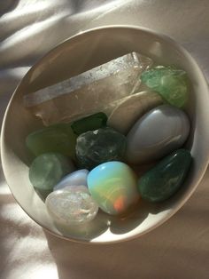 a white bowl filled with lots of different colored rocks and stones on top of a table