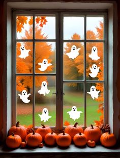 a window decorated with halloween ghost stickers and pumpkins