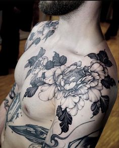 a man's chest with flowers and birds tattooed on his chest, in black and white