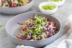 two bowls filled with coleslaw and sprouts on top of a table