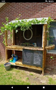 a wooden bench sitting in front of a brick building next to a potted plant