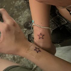 two people with matching tattoos on their wrists, one holding the other's hand