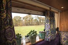 there are many plants on the window sill in this rv's living room