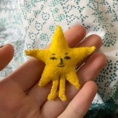 a person holding a small yellow felt star in their left hand, with eyes drawn on it