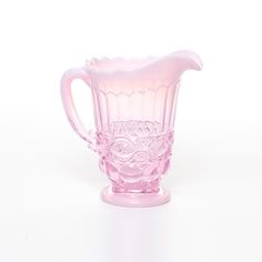 a pink glass pitcher sitting on top of a table