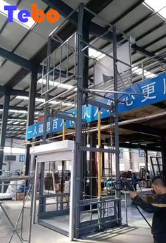 the inside of an industrial building with workers working on metal structures and signs above it