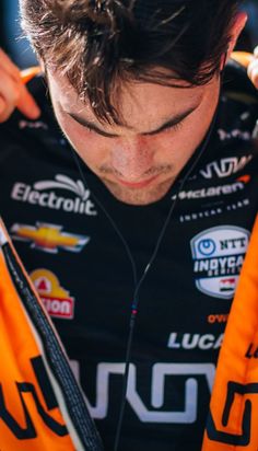 a close up of a person wearing an orange and black jacket with ear buds in his ears