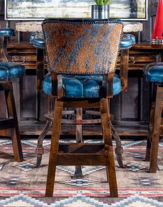 a wooden table topped with blue chairs and a vase filled with flowers on top of it