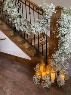 some candles are sitting on the floor next to a stair case with flowers and baby's breath