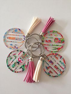 four circular keychains with tassels on them sitting on a white surface