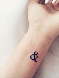 a woman's wrist tattoo with the letter q on her left hand and an arrow in the middle