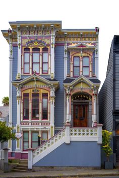 an old victorian style house painted in blue and yellow with red trim on the windows