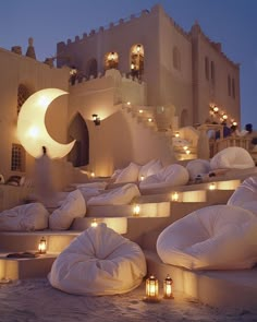 an outdoor seating area with lit candles on the ground and inflatable bean bag chairs