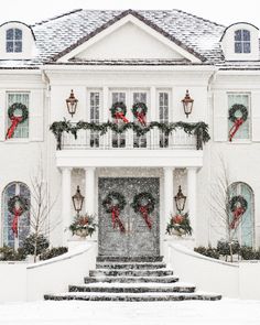 a large white house covered in snow with wreaths