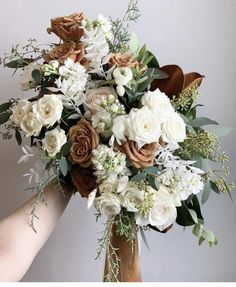 a bouquet of white and orange flowers in a vase with greenery on the side