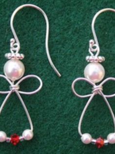 pair of earrings with bow and pearls on green carpeted floor next to red crystal beads