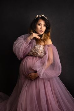 a pregnant woman in a purple gown poses for the camera with her hands on her belly