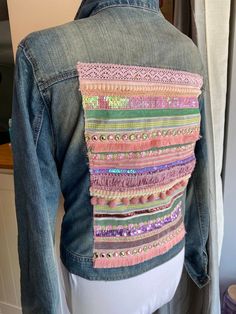 a woman's jean jacket with multicolored sequins on the back