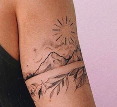 a woman's arm with a tattoo on it and mountains in the distance behind her