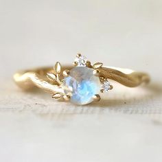 a close up of a ring with an opal and leaves design on the side