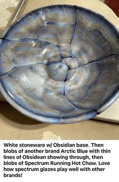 a blue bowl sitting on top of a table next to a white plate with writing underneath it