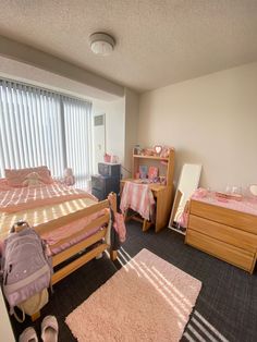 a bedroom with two beds, dressers and a rug on the floor in front of a window