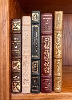 a row of books sitting on top of a wooden book shelf next to each other