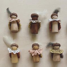 several wooden dolls are lined up on the wall with feathers in their hair and dresses