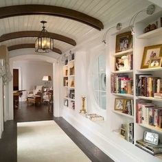 the hallway is lined with bookshelves and pictures on the wall, along with a lamp