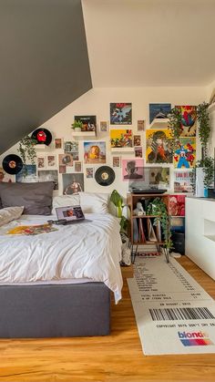 a bed sitting under a slanted ceiling with pictures on the wall next to it