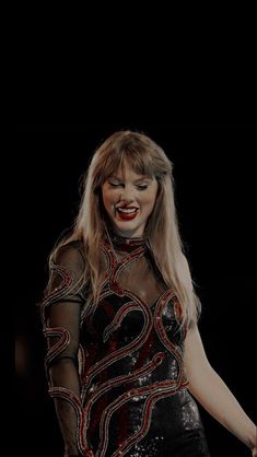 a woman in a black and red dress with her hands out to the side, smiling