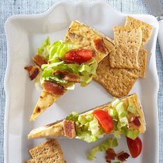 a white plate topped with crackers, salad and bacon on top of lettuce