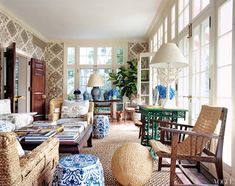 a living room filled with lots of furniture next to a window covered in plants and flowers