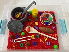 a plastic container filled with lots of different types of letters and spoons on top of red carpet