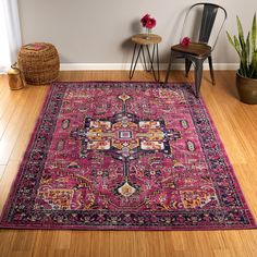 a pink rug with an ornate design on the floor next to a chair and potted plant