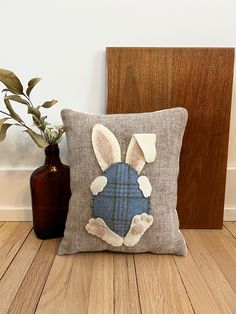 a pillow with a bunny's head on it next to a brown vase