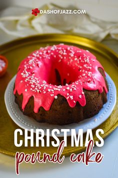 a christmas pound cake with pink frosting and sprinkles on a gold platter