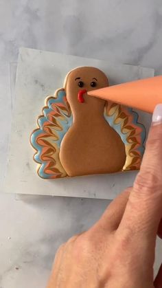 a hand holding a cookie shaped like a turkey