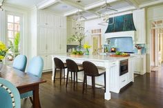 a large kitchen with white cabinets and blue chairs in the center island, surrounded by wood flooring