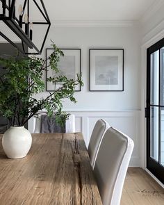 a dining room table with chairs and pictures on the wall in front of it's windows