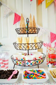 a table topped with lots of desserts next to bunting and paper streamers