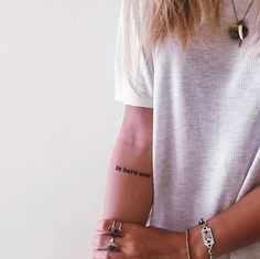 a woman with tattoos on her arm holding onto a cell phone and wearing a white t - shirt