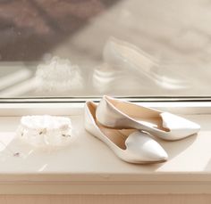 a pair of white shoes sitting on top of a window sill next to a flower