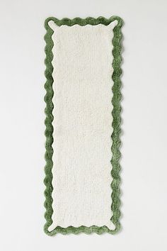 a green and white rug with scalloped edges