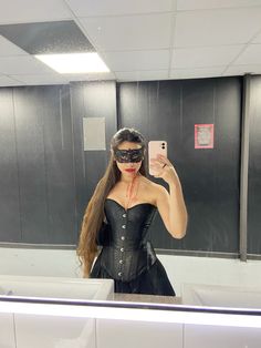 a woman in a corset takes a selfie with her phone while wearing a blindfold