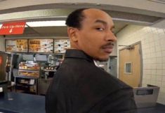 a man standing in front of a counter with a tv on it's side