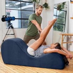 a man standing next to a woman laying on top of a black bean bag chair