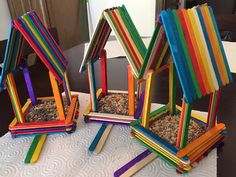 three colorful bird feeders on top of a table with sticks sticking out of them